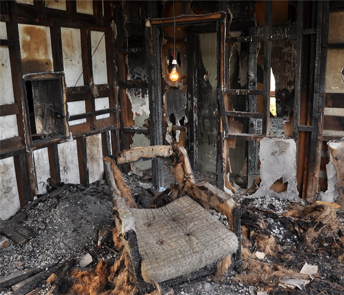 a fire damaged living room with debris on the floor and soot everywhere