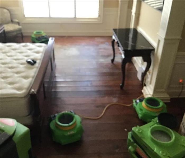 SERVPRO drying equipment in bedroom.  Water damaged hardwood floor.